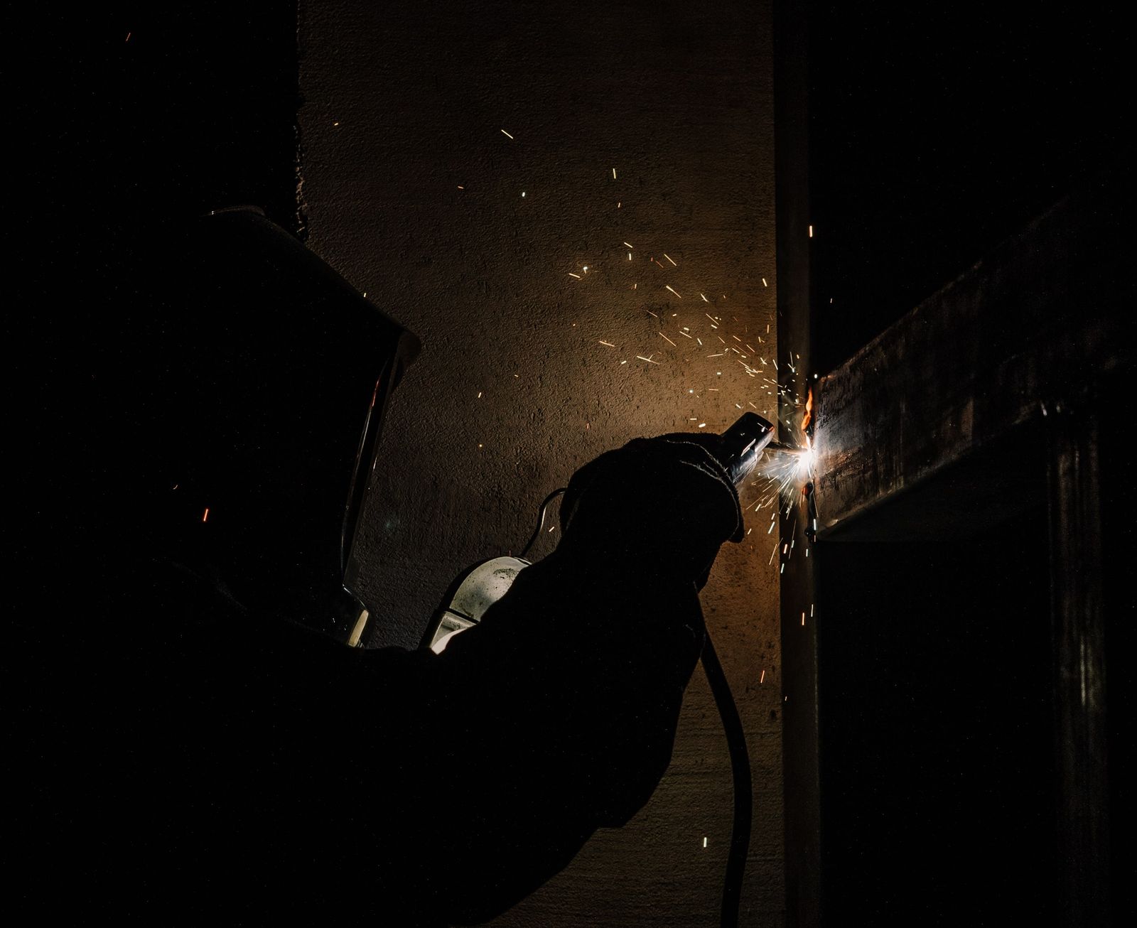 Robotic welding arc lighting a dark factory floor
